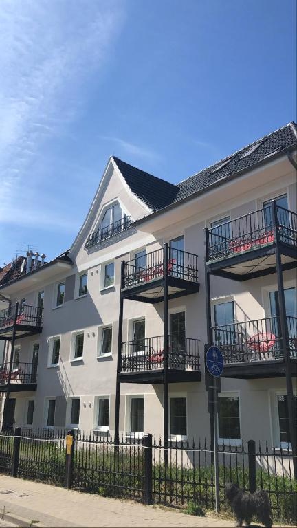 Das Haus der Ostseestrand-Apartments: weiße Fassade, anthrazitfarbenes Dach, umlaufende Balkone