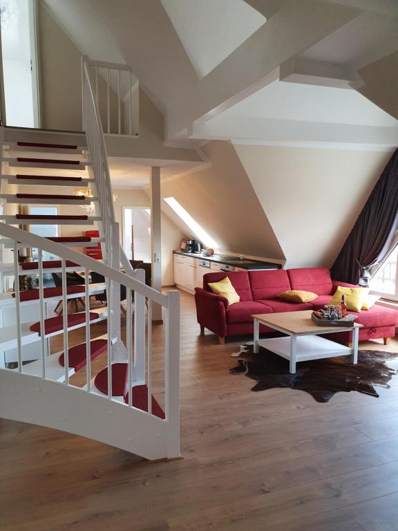 Wohnbereich der Maisonette mit Wendeltreppe und rotem Sofa