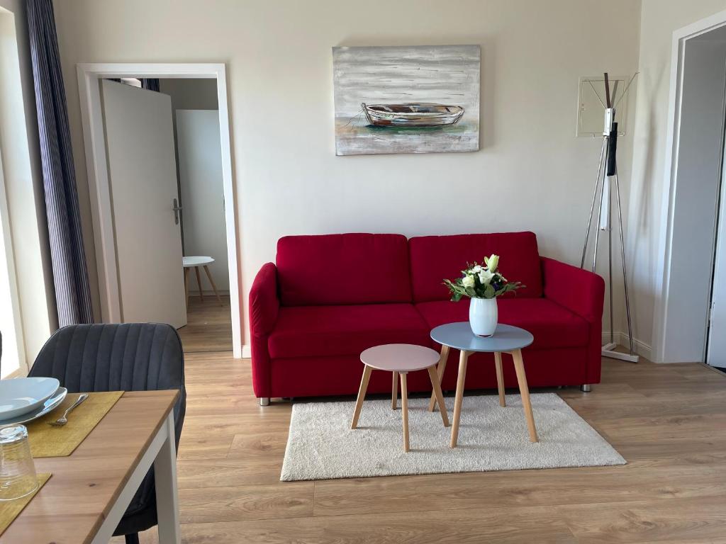Wohnzimmer mit rotem Sofa und Durchgang zum Schlafzimmer