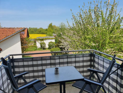 Balkon mit Tisch und Stühlen ins Grüne